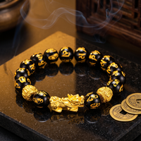 Feng Shui obsidian bracelet with gold Pi Xiu on a dark surface