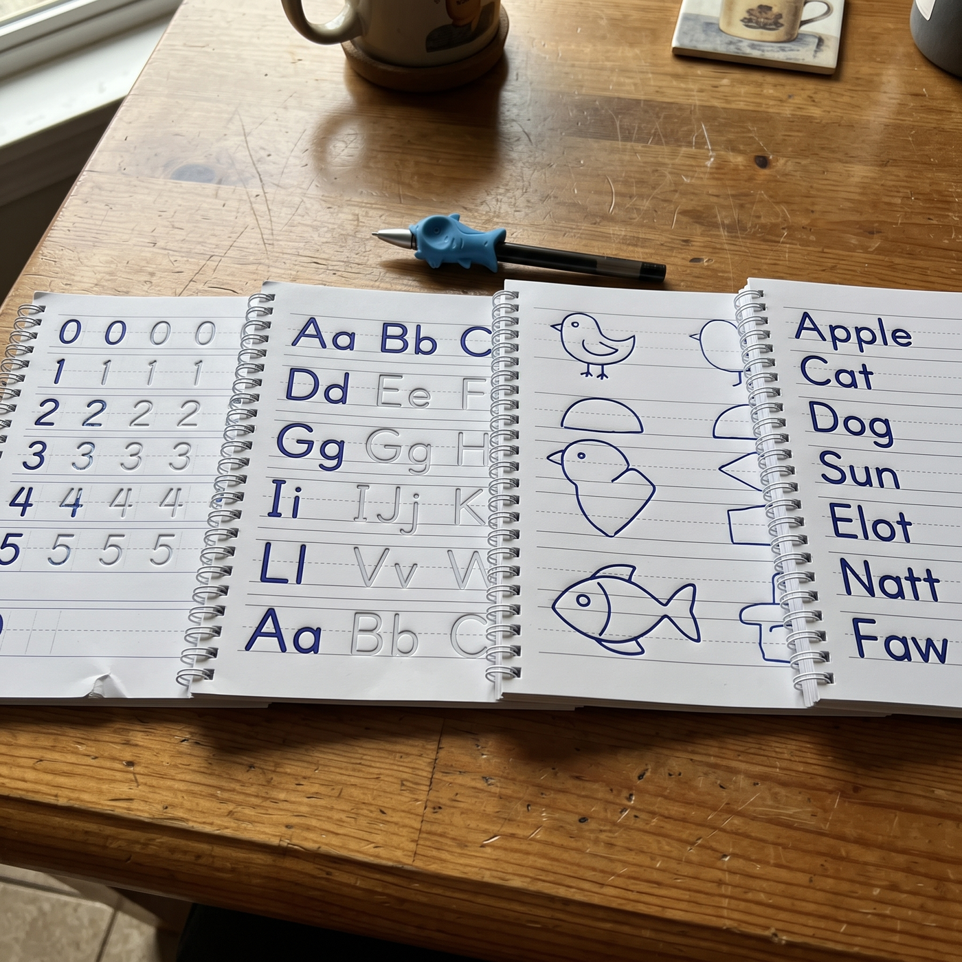 The four practice copybooks showing numbers, letters, drawing and English
